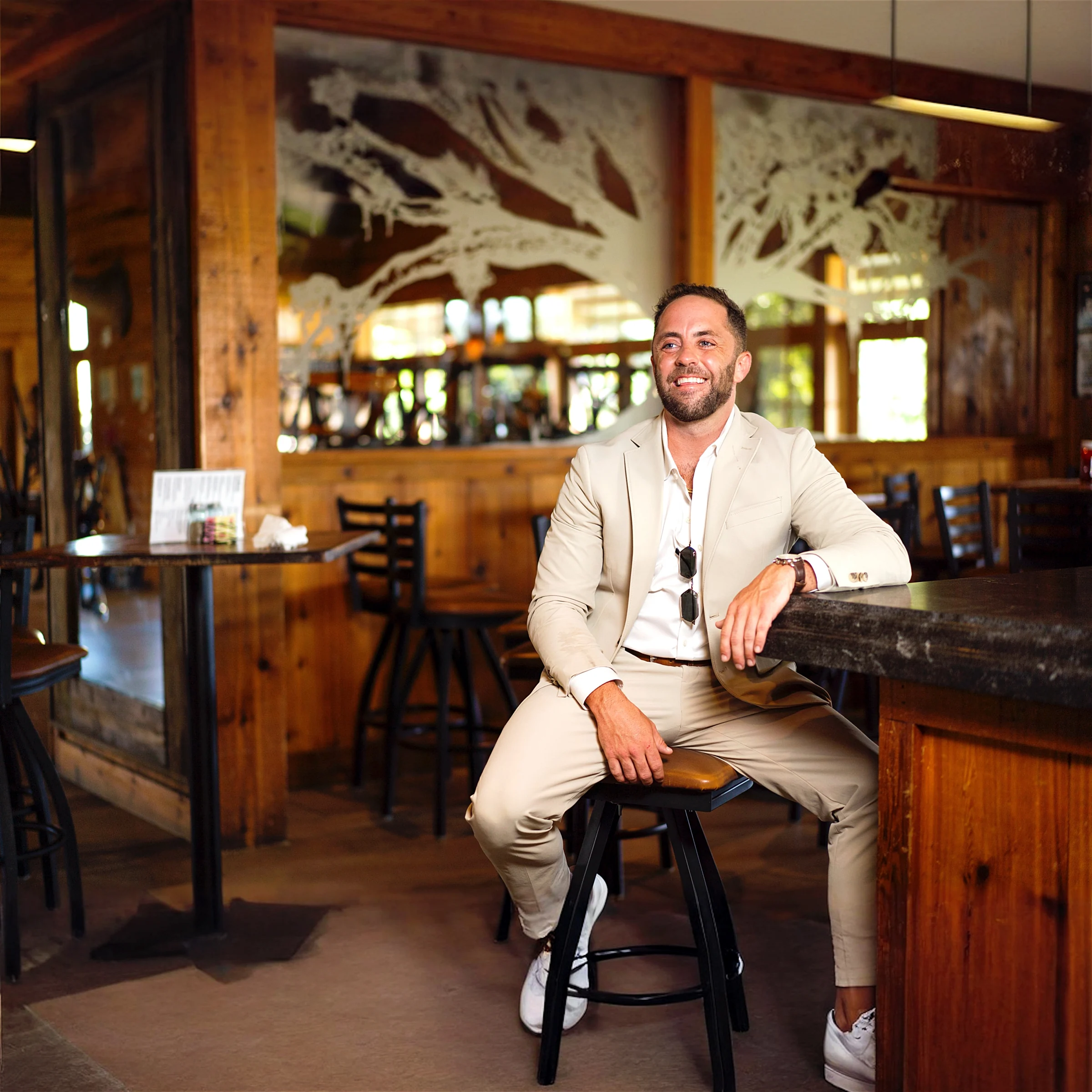 Caleb Jackson seated at a bar in a tan suit